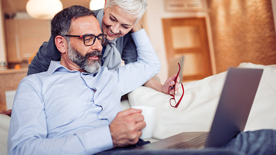 Couple looking at the computer together on the sofa